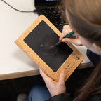 A person writing on a notebook’s LCD screen