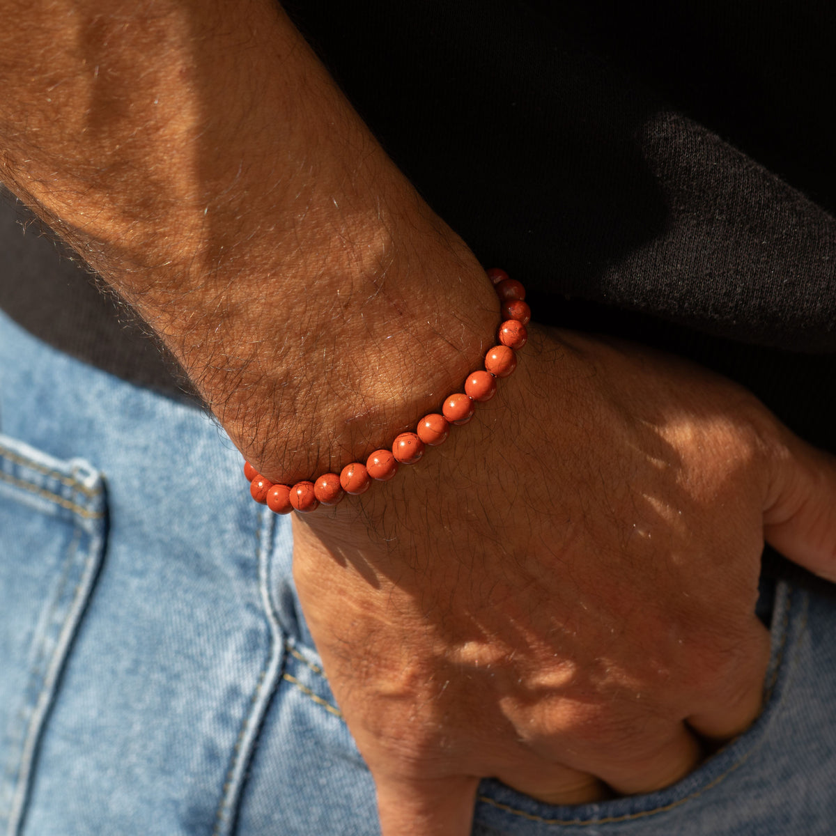 Carnelian bracelet worn on a wrist beside a pocket