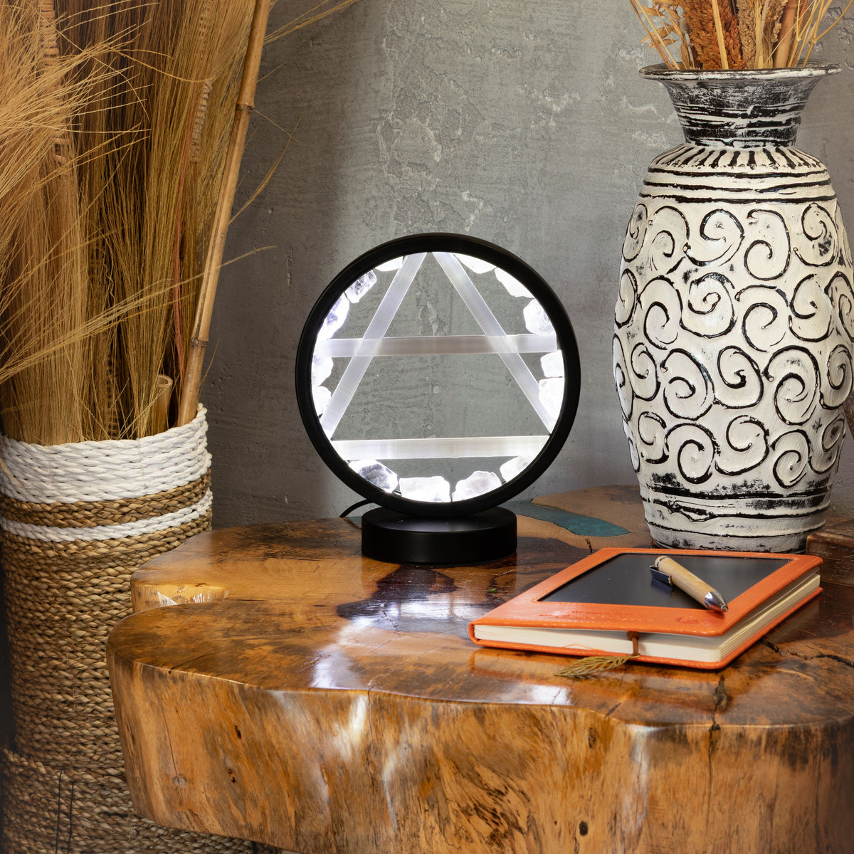 Lamp displayed on a wooden table beside a vase and notebook