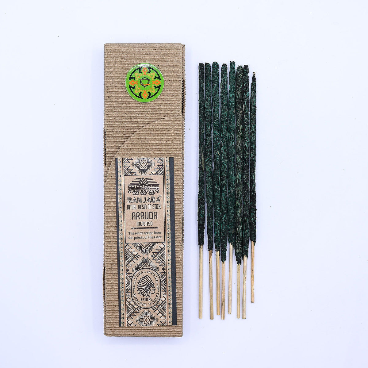 Ritual Resin on Stick, Arruda in a kraft box beside dark green sticks on a pale background