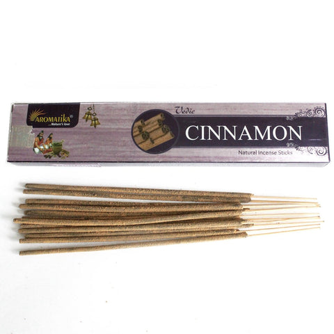 Vedic Cinnamon Incense Sticks in a horizontal box beside loose brown sticks on a white background