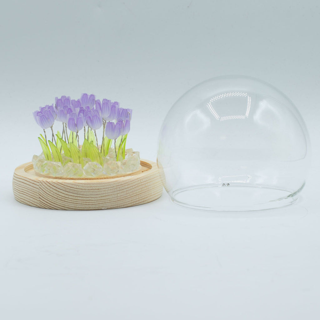 Garden dome with purple tulips on a wooden base beside its clear glass cover