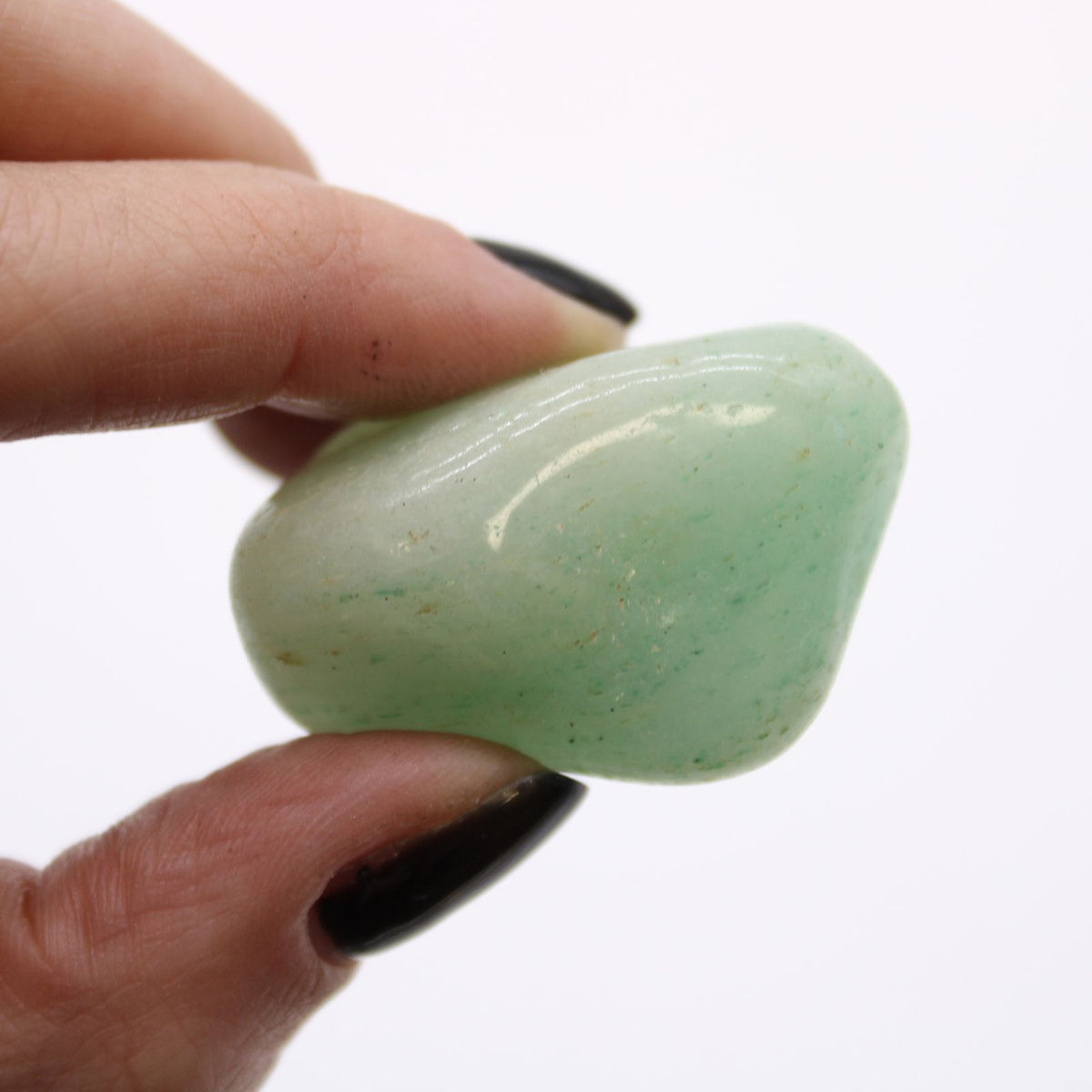 Medium African Tumble Stones, Aventurine, a pale green polished stone held between fingers in close-up