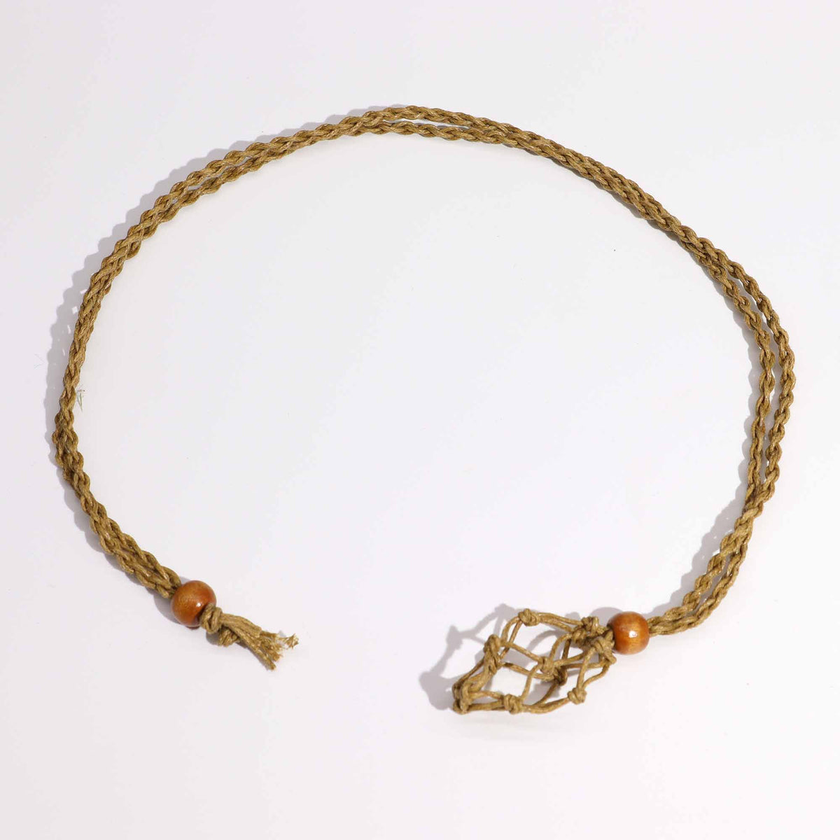 Sand necklace cord laid in a loop on white, showing its knotted fastening and brown beads