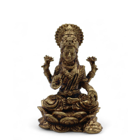 Laxmi miniature shown from the front, seated on a lotus base with a small ornament beside it
