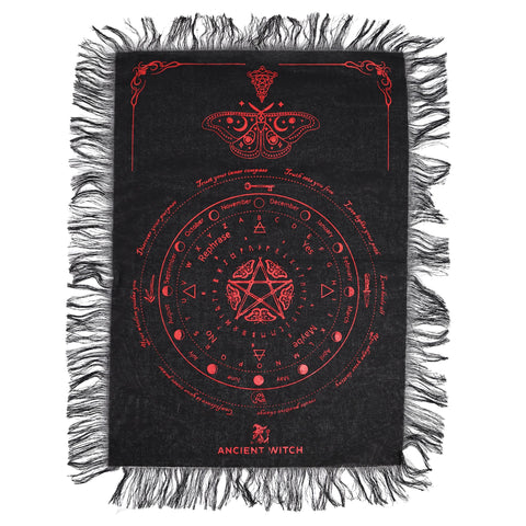 Black and blood red divination cloth laid flat, showing its moth design, circular symbols and fringed edges