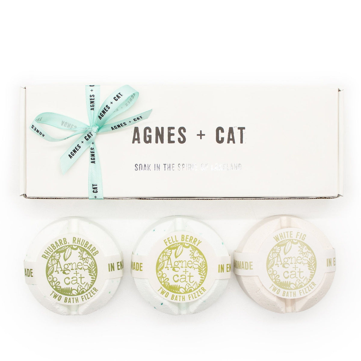 Gift set viewed from the front, with a white ribbon-tied box and three wrapped fizzers on white