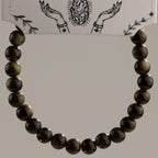 Gold Obsidian beads arranged in a bracelet beneath the card