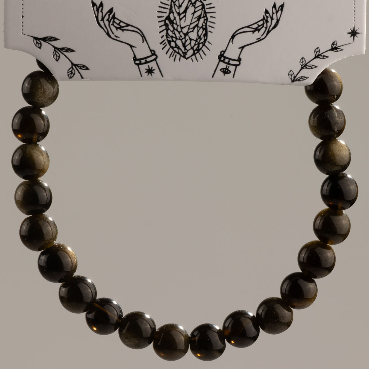 Gold Obsidian beads arranged in a bracelet beneath the card