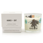 Agnes + Cat Sea Salt and Moss soy candle in a glass jar with dried florals set in the wax, beside its box.