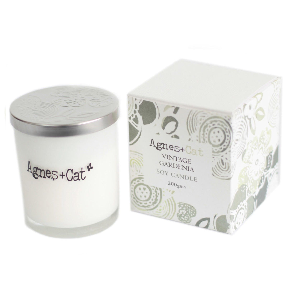 Agnes + Cat Votive Candle, Vintage Gardenia, white candle with silver lid beside patterned box