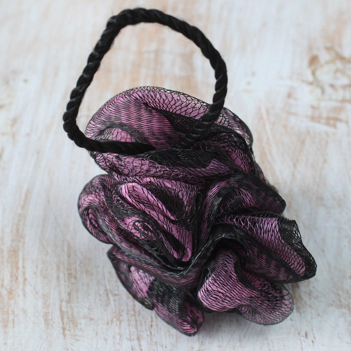 Luxury Scrunchie in black and pink mesh with a black hanging loop, resting on a pale wooden surface