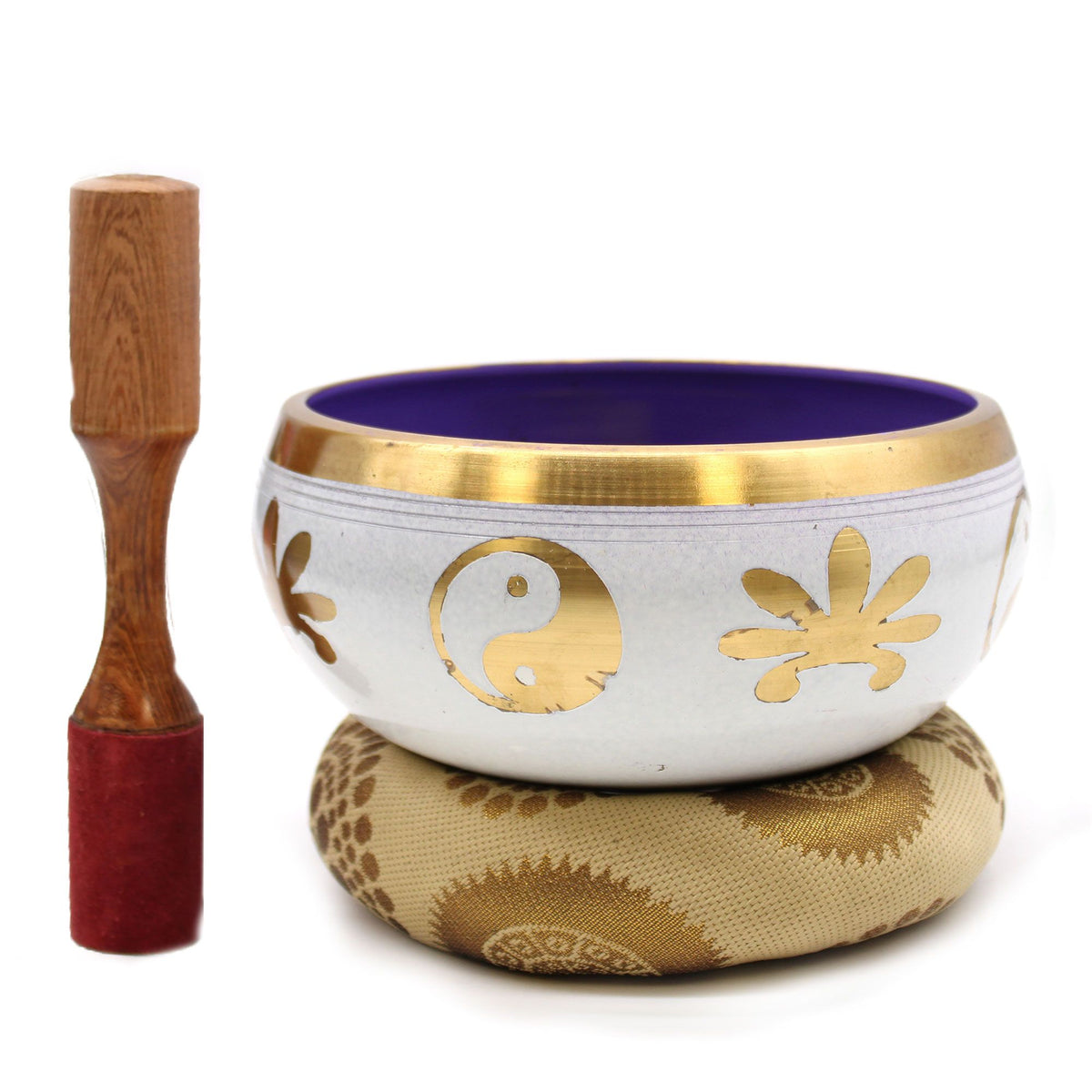 White and purple singing bowl with gold symbols, cushion and wooden striker arranged against a white background