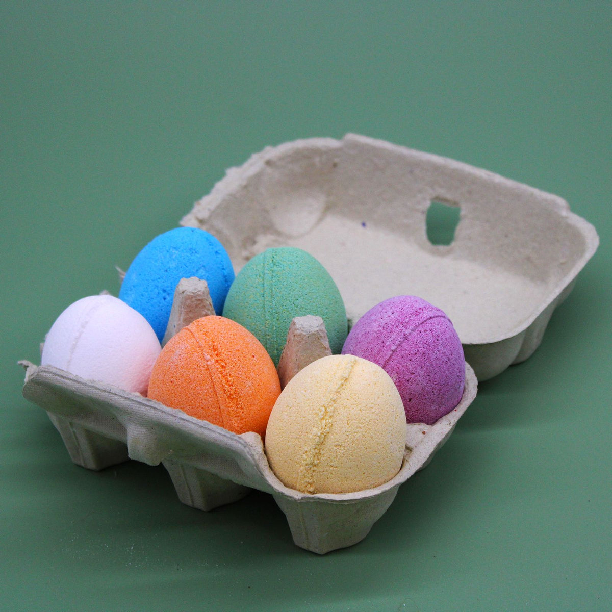 Bath eggs in an open cardboard tray, six in orange, blue, green, pink, yellow and white
