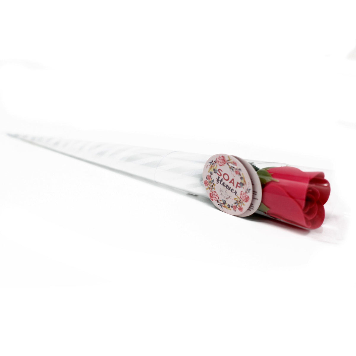 A single wrapped red soap flower rose lying on its side