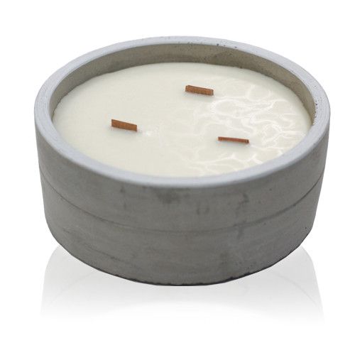 Round grey concrete candle with three wooden wicks and white wax, shown alone on a white reflective surface