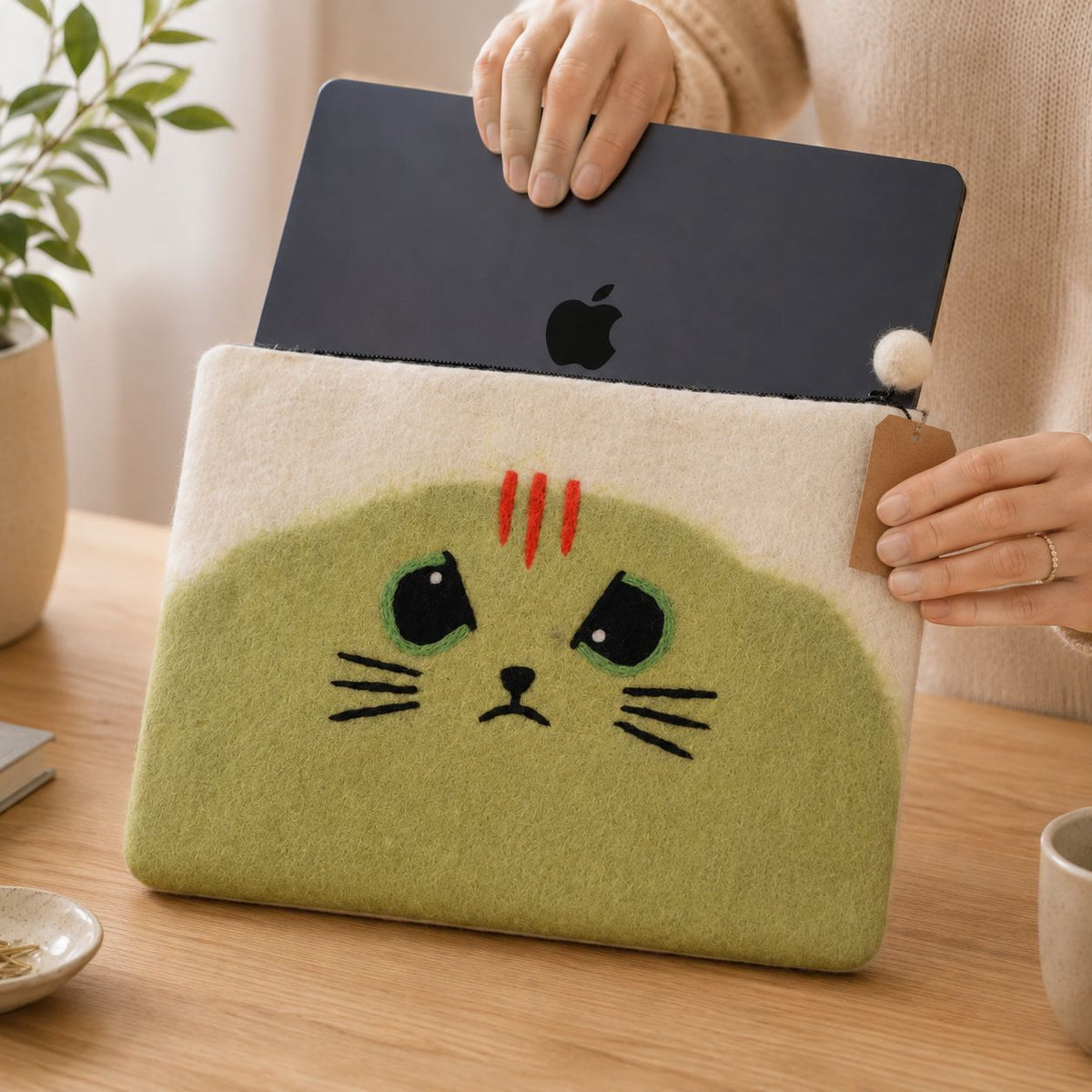 Laptop being placed into the Unimpressed Cat felt pouch