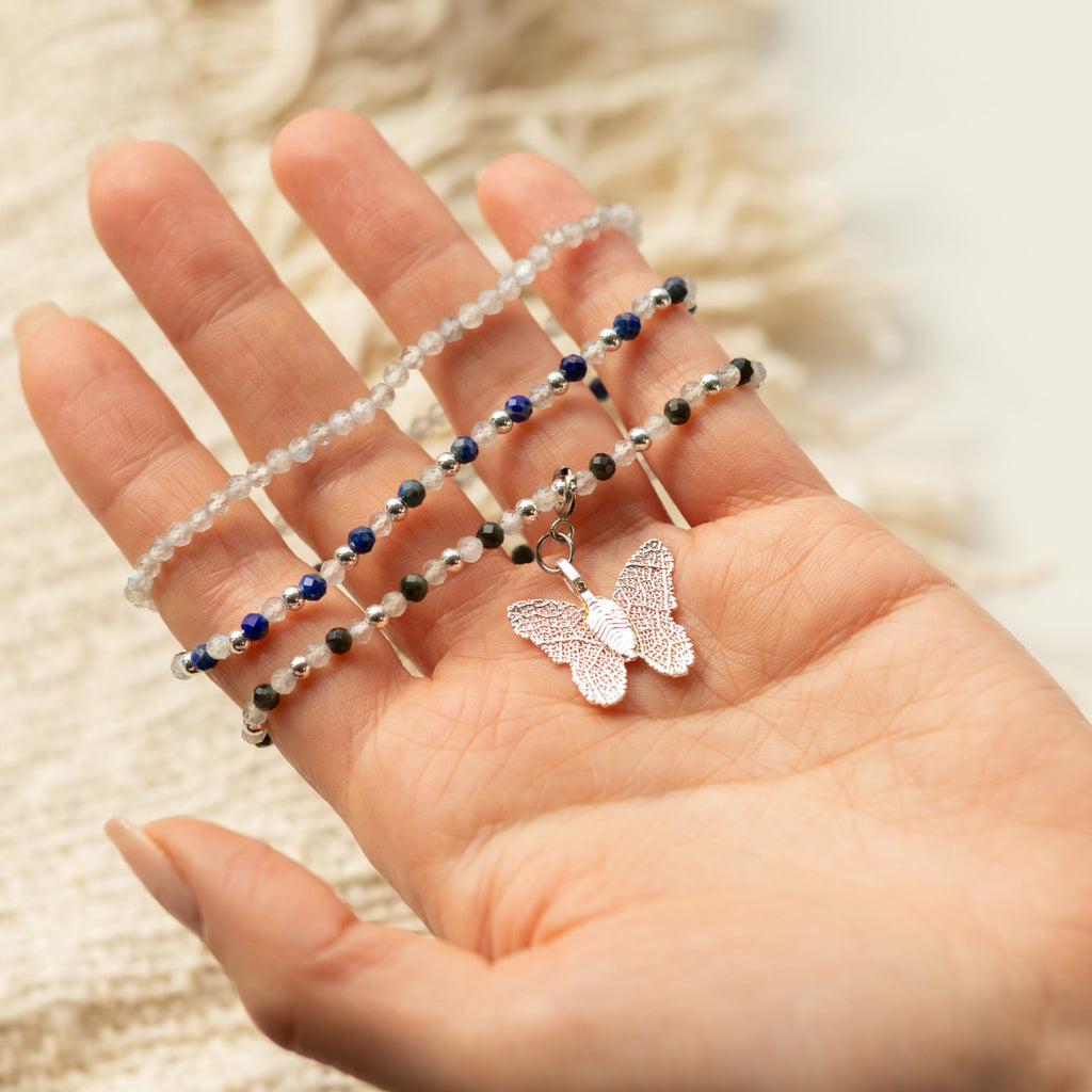 Three bracelets and butterfly charm displayed on a hand