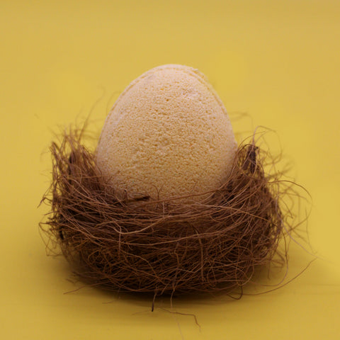 6 Bath Eggs in a Tray, Banana, one pale peach egg nestled in brown fibres against a yellow background