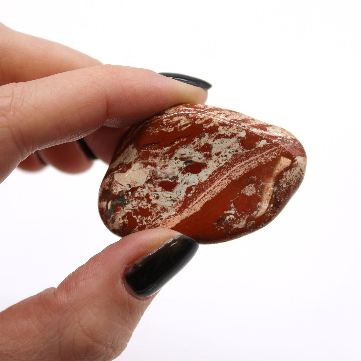 Large African Tumble Stones, Light Jasper, Brecciated, one reddish patterned stone held between fingers
