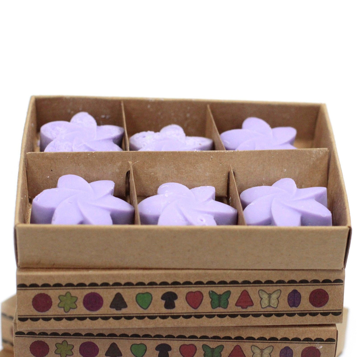 Close view into the open kraft box, six lilac flower melts sit in separate compartments