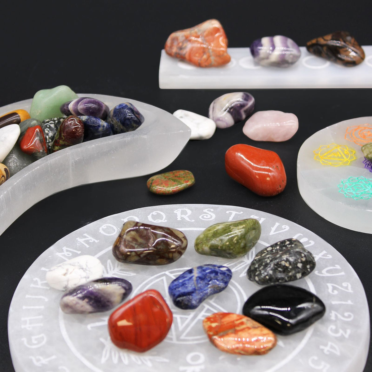 Medium African Tumble Stones, Grey Agate, Botswana, a grey banded stone among colourful stones on crystal plates