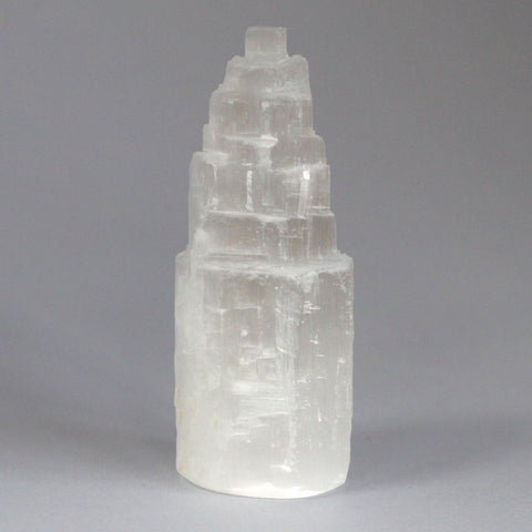 Close-up of the pale translucent selenite tower against a plain grey background