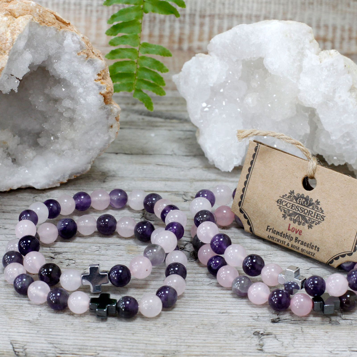 Set of 2 Gemstones Friendship Bracelets, Love, Amethyst & Rose Quartz on a wooden surface with crystal clusters