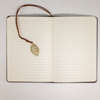 Open notebook showing lined pages and leaf bookmark