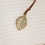 Brass-coloured leaf bookmark against lined notebook pages