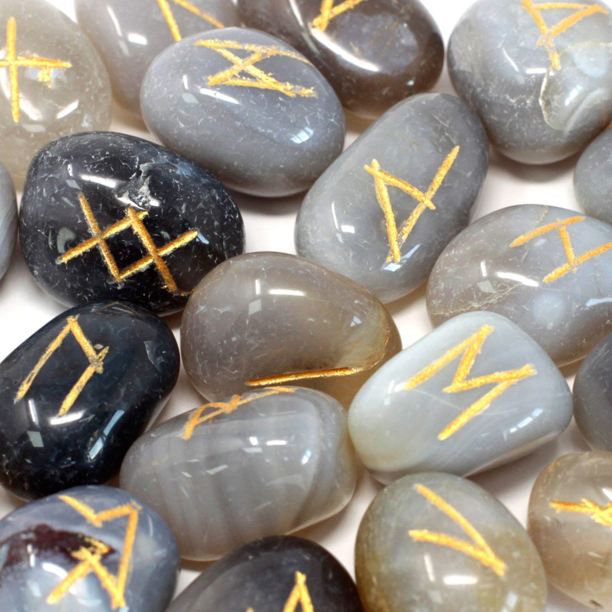 Runes Stone Set in Pouch, Grey Agate, close-up of grey and dark stones with gold runes