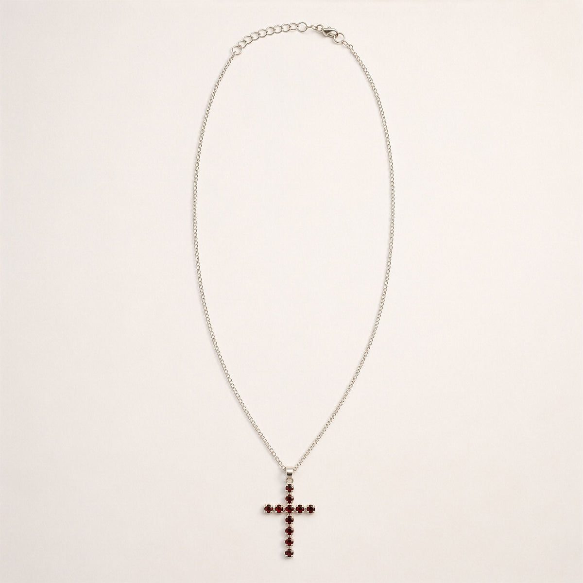 Full silver-coloured chain displayed in a loop with the garnet crucifix pendant hanging at the centre