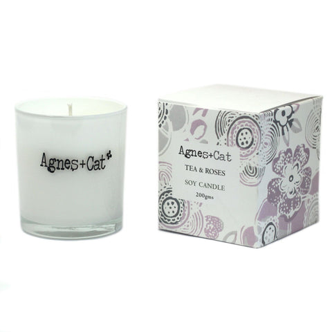 Agnes + Cat Votive Candle, Tea and Roses in a clear glass votive beside its floral box