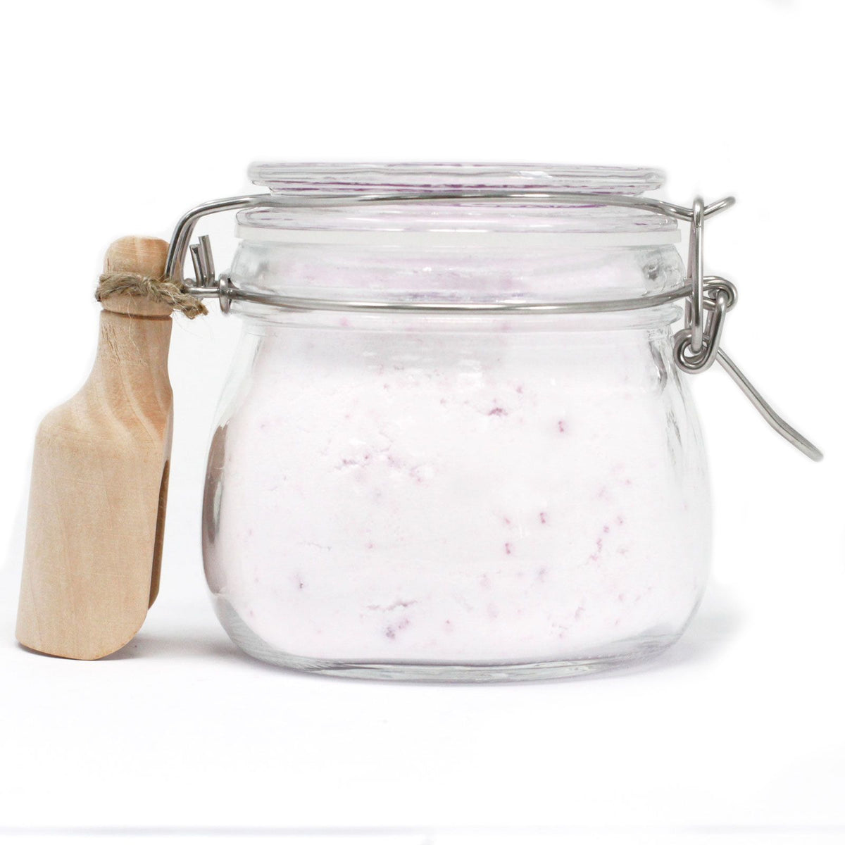 Side view of the clear fairy dust jar with pale pink-flecked powder, metal clasp and wooden scoop