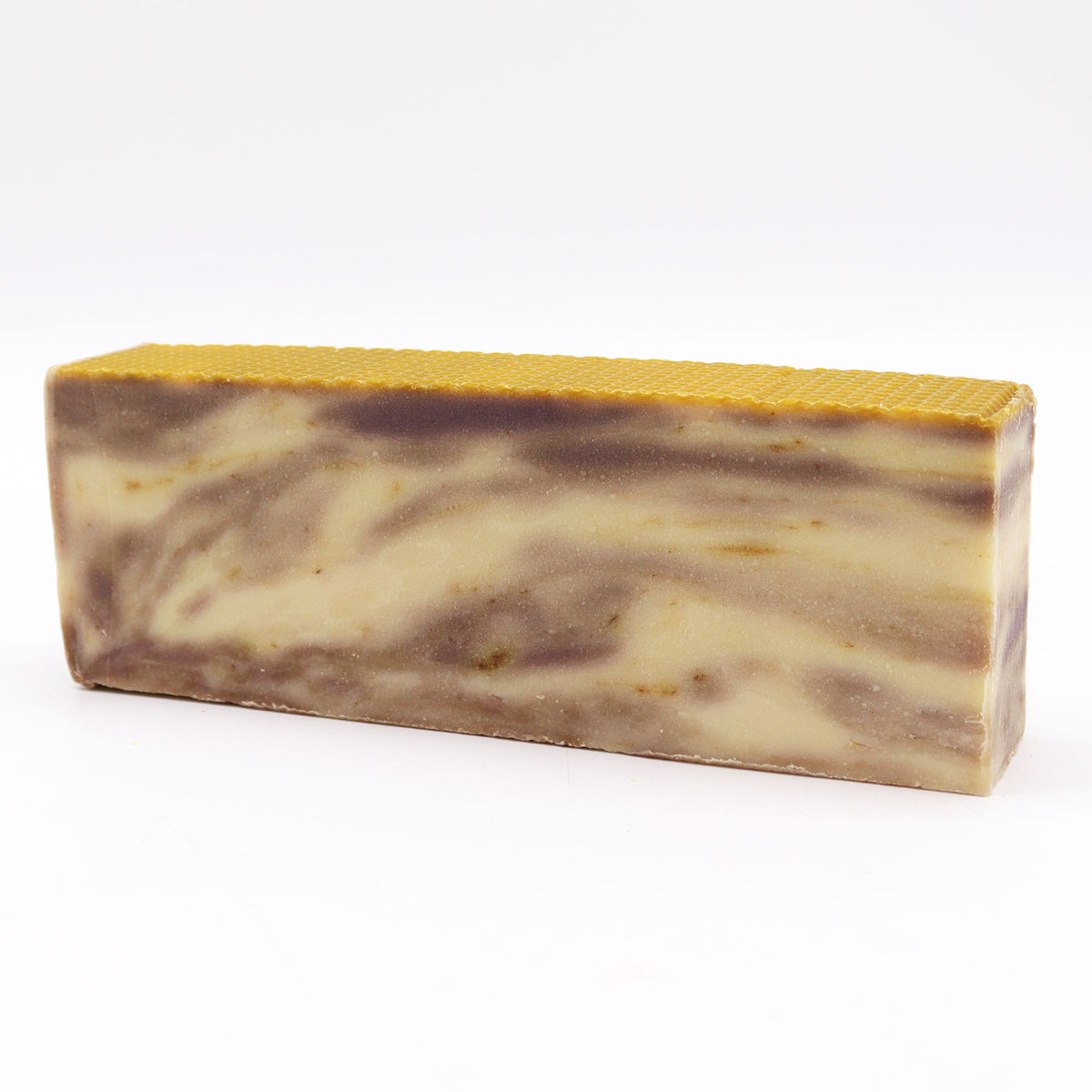 Propolis soap loaf shown whole from the front, with a golden top and cream and brown marbling