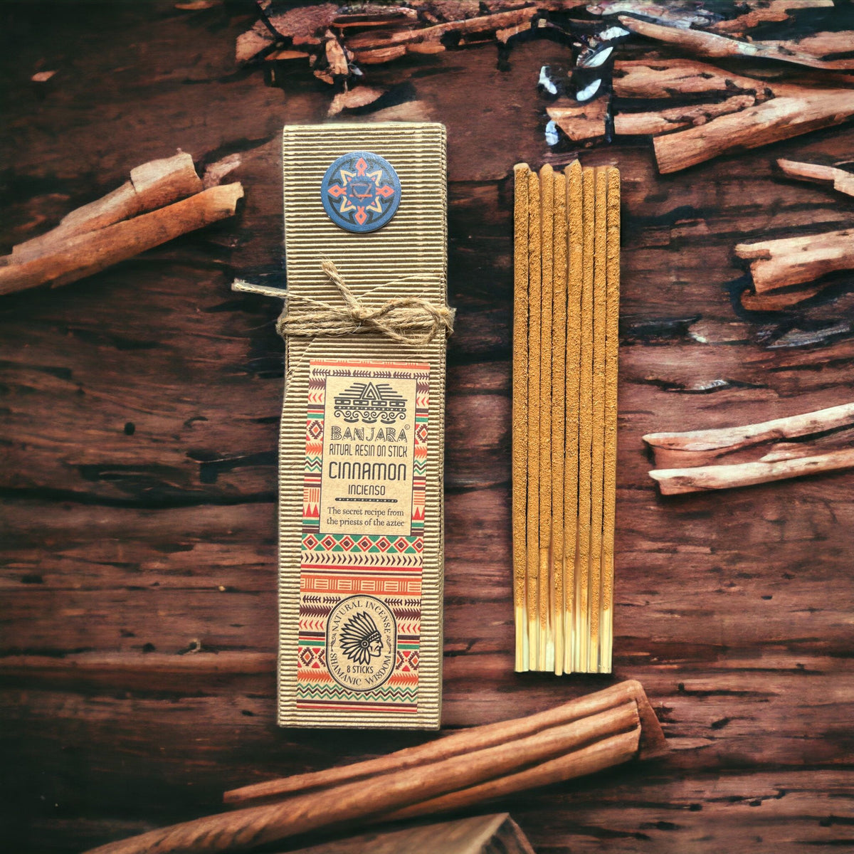 Ritual Resin on Stick, Cinnamon in a patterned paper sleeve beside a bundle of incense sticks