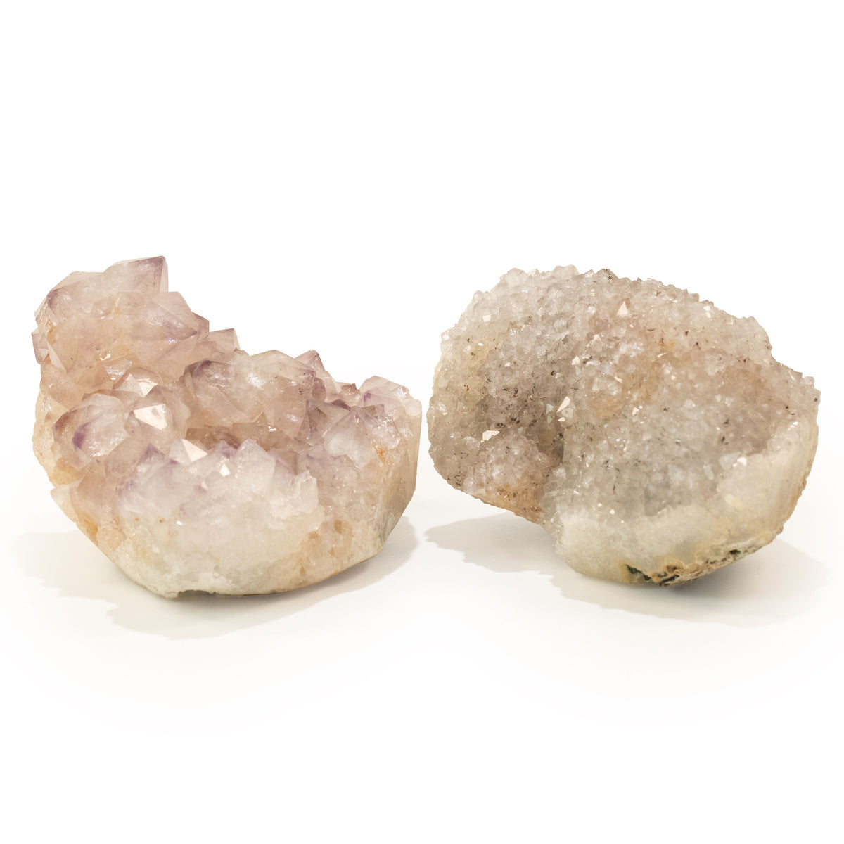 Two assorted geodes against a white background, with lavender crystals on one and a grey crystal cavity on the other