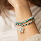 Layered bracelets and butterfly charm on a wrist