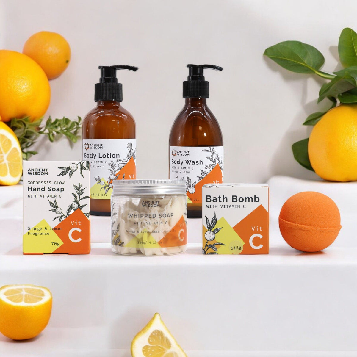 Vitamin C bath and body bundle arranged with orange and lemon products, amber bottles, a soap jar and an orange bath bomb