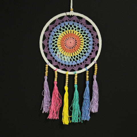 The Small Dreamcatcher in Pastel Rainbow, hanging against a black background
