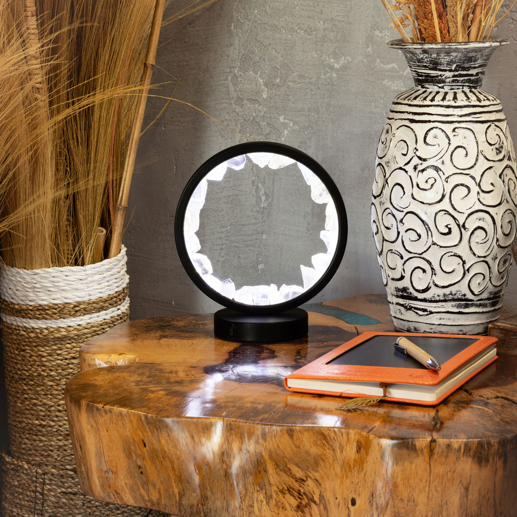 Halo lamp displayed on a table beside a vase and notebook