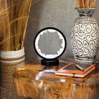 Halo lamp displayed on a table beside a vase and notebook