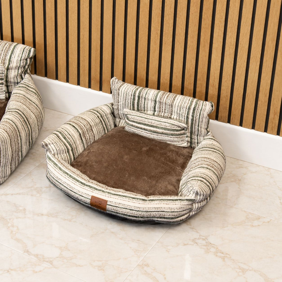 Close view of the striped pet bed and its rounded armrests