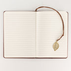 Notebook opened to show lined pages and leaf bookmark