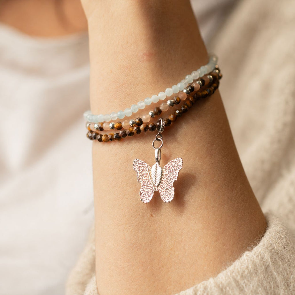 Close view of the bracelets and butterfly charm on a wrist