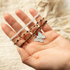 Bracelets and butterfly charm shown across a hand