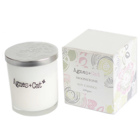 Moonstone candle with a silver patterned lid beside its matching pastel patterned box