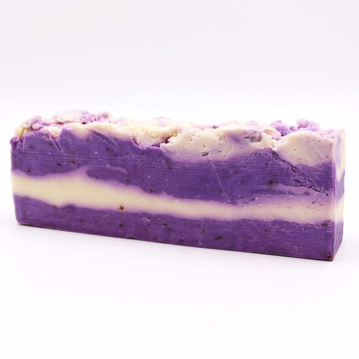 Lavender soap loaf shown from the side, with purple and cream layers and a textured top