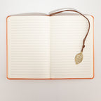 Open notebook showing lined pages and a leaf bookmark