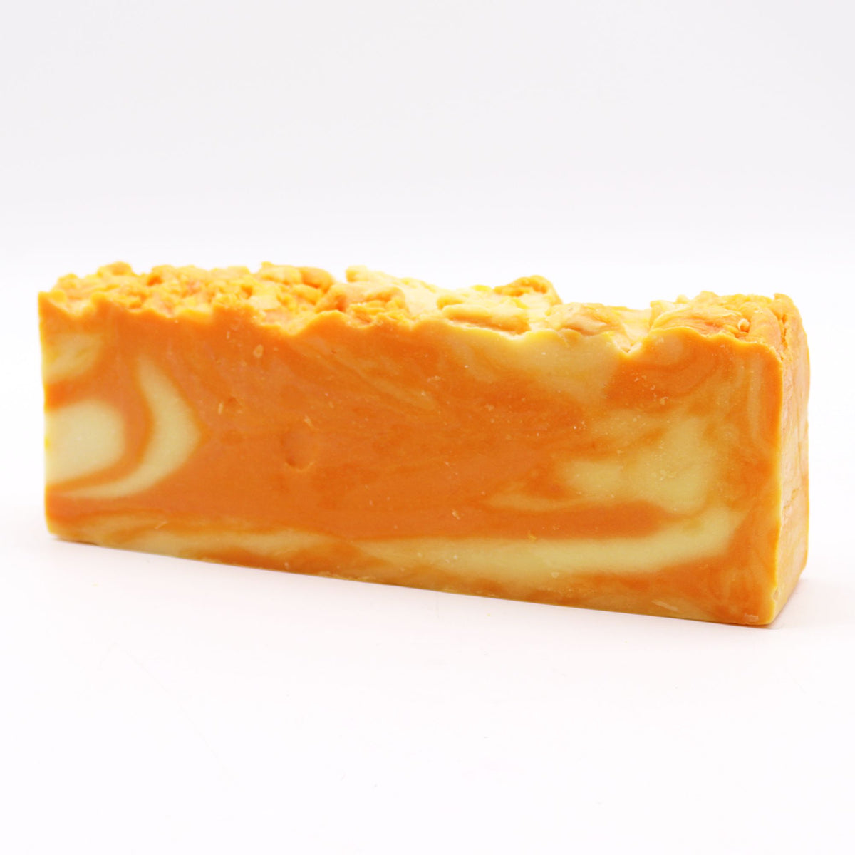 Orange olive oil soap loaf shown from the front, with a textured top and cream swirls